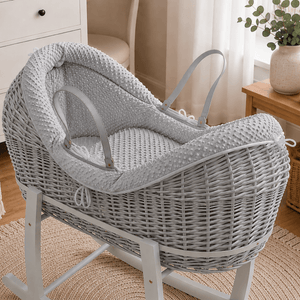 Grey wicker baby moses basket on white stand with padded grey waffle bedding