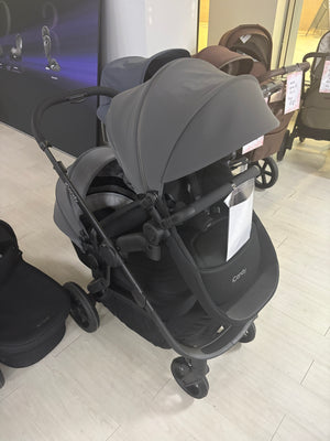 Grey pushchair with attached carrycot and seat, front three-quarter view, stroller wheels