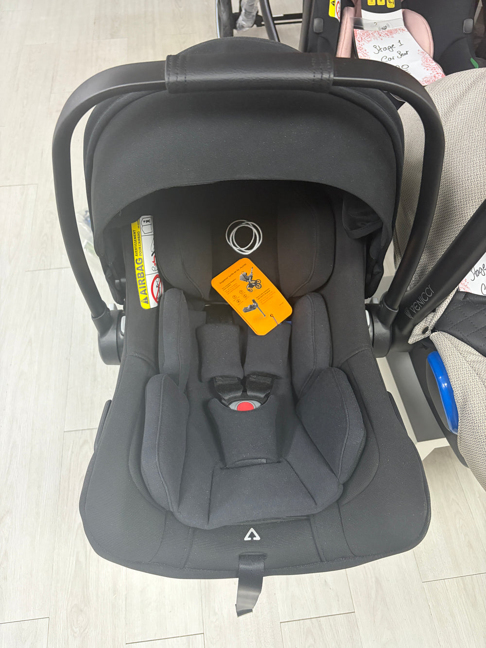 Black baby car seat with canopy, padded harness, and recline base
