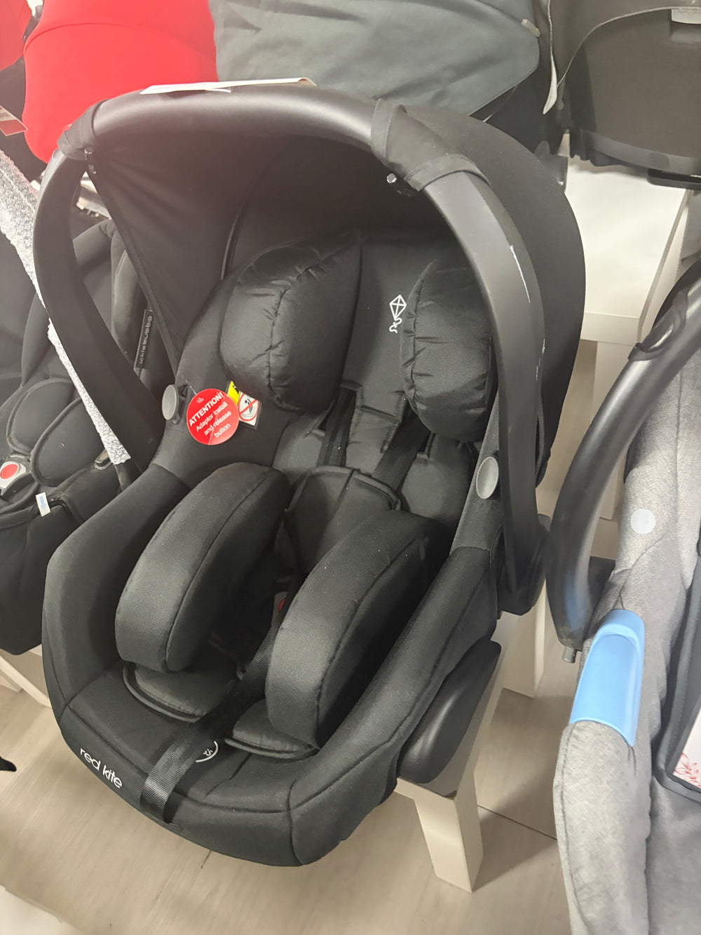 Red Kite newborn car seat with black padded inserts and 5-point harness, front view
