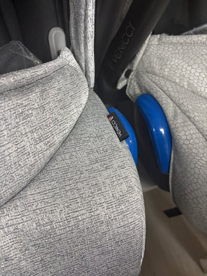 Grey newborn car seat side with blue handle and textured shell