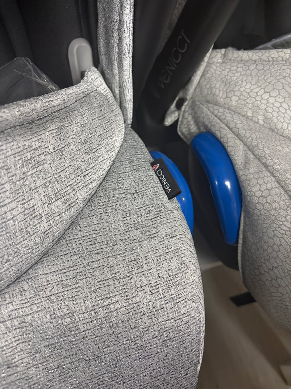 Grey newborn car seat side with blue handle and textured shell