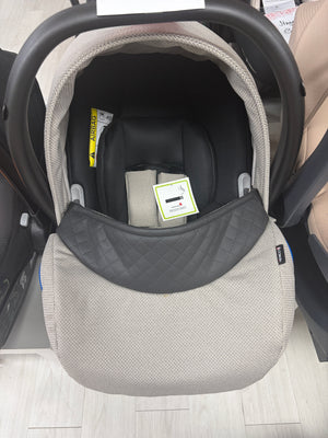 Newborn car seat carrier with beige knit shell and dark gray headrest