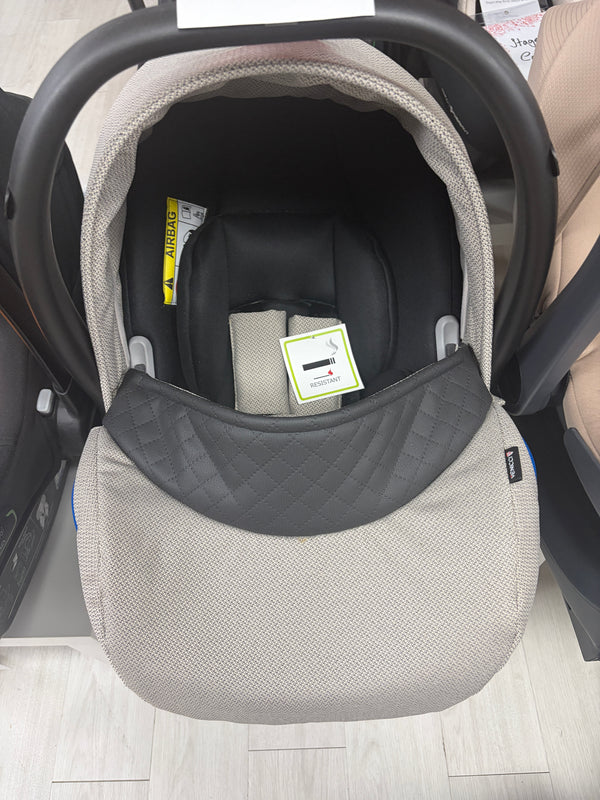 Newborn car seat carrier with beige knit shell and dark gray headrest
