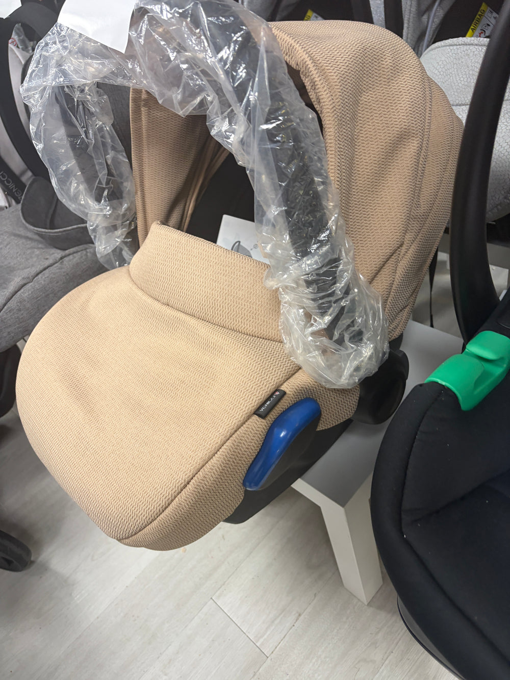 Cream newborn car seat with padded insert, wrapped in protective plastic