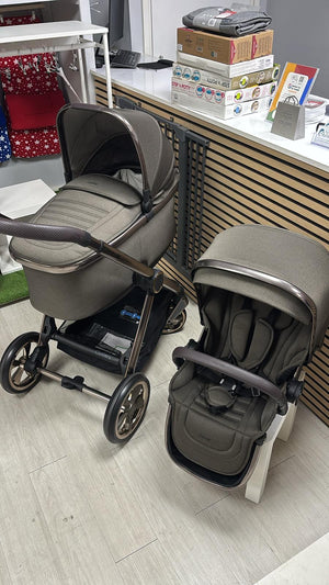 Two gray strollers with padded seats and bassinet, black frames, and multiwheel base