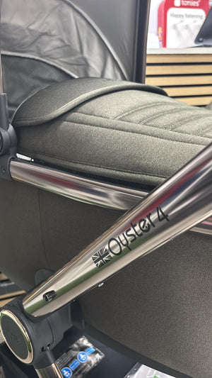 Gray padded stroller seat with canopy, silver metal frame, and visible brand lettering