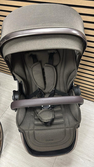 Gray stroller bassinet with canopy and padded headrest, front harness strap detail