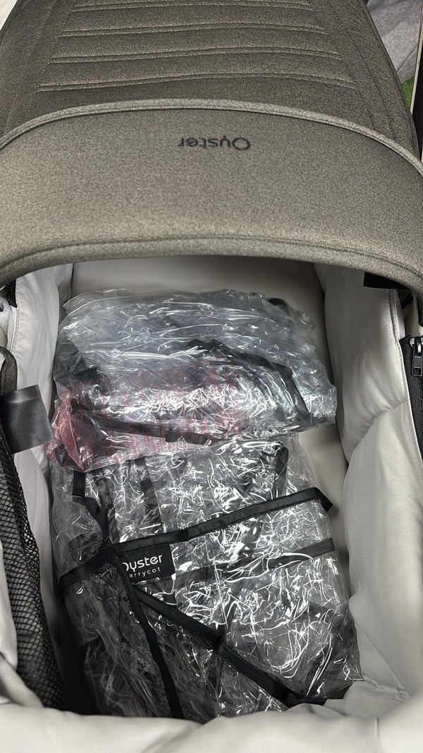 Gray stroller canopy open, showing bundled accessories in clear plastic bags