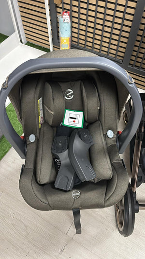 Gray infant car seat with head support and harness, mounted on stroller base frame