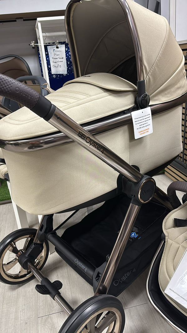 Beige stroller seat with dark handle and wheels, angled close-up