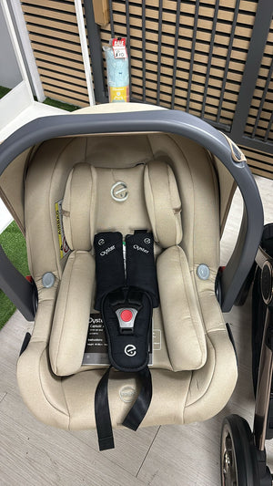 Beige infant car seat with harness and headrest, front view