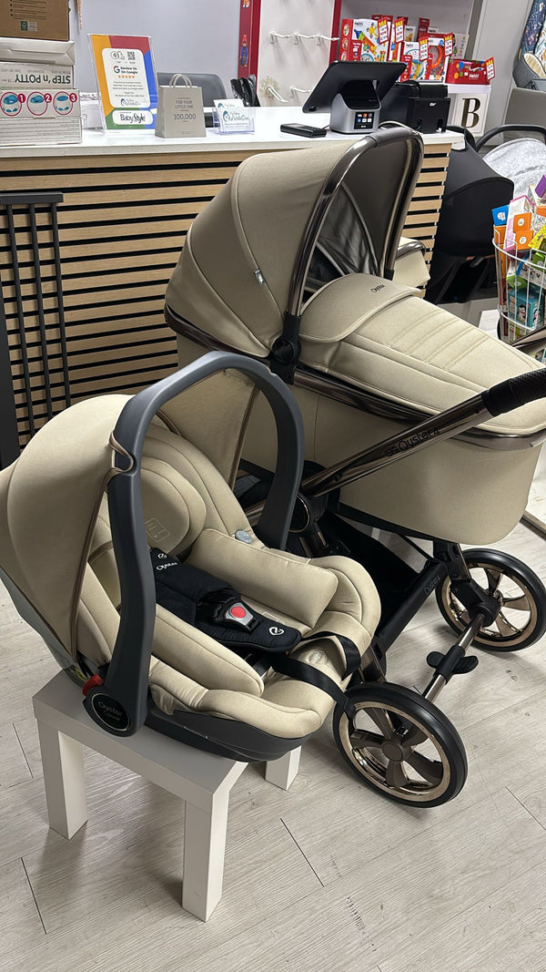 Beige stroller system on display with car seat and base nearby