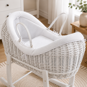 White wicker baby crib in a nursery with toys and decor.