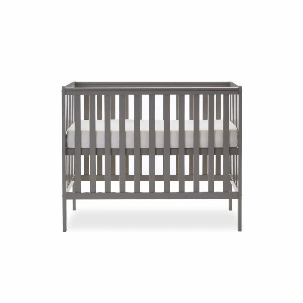 Taupe grey baby cot with vertical slats, raised rail, grey padded mattress, blanket